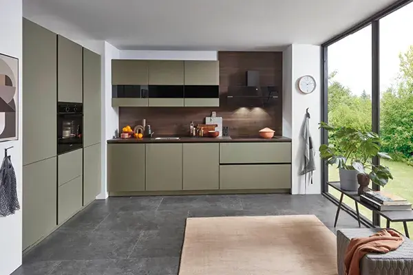 Moderne Designküche in U-Form mit mattgrünen Fronten, schwarzer Glasabzugshaube und Holzrückwand. Großzügige Fensterfront, viel Stauraum, hochwertige Küchengeräte – stilvolle Küche für zeitgemäßes Wohnen.